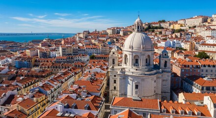 Fototapeta premium Panthéon National de Lisbonne dominant le quartier historique de l'Alfama, vue aérienne panoramique sur les toits rouges et le fleuve Tage sous un ciel bleu éclatant.