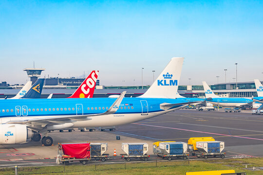 Amsterdam, Netherlands - 22.01.2026: KLM and Corendon airplanes at the gates with baggage carts and cargo containers at Amsterdam Schiphol Airport