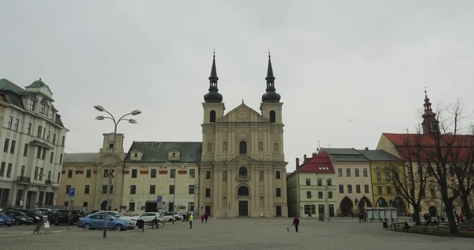 Jihlava, Czech Republic - April 15, 2026: A wide view of a historic European town square featuring a prominent twin-spire church and colorful architecture under an overcast sky
