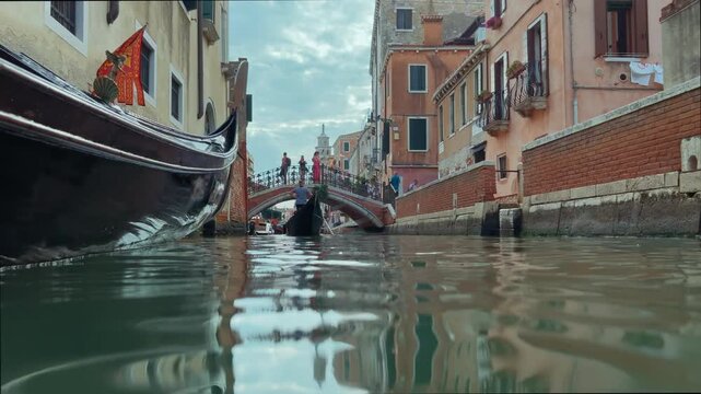 Quiet Waterway Beneath Arched Bridge. Tourists Cross Small Bridge Over Narrow Venetian Water Corridor