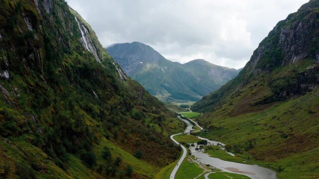 Aerial view of empty winding Road next to a river flowing through deep mountain canyon in Klakegg, Norway. Epic summer wilderness landscape for indie travel and wild tourism. 4K tilt down drone shot