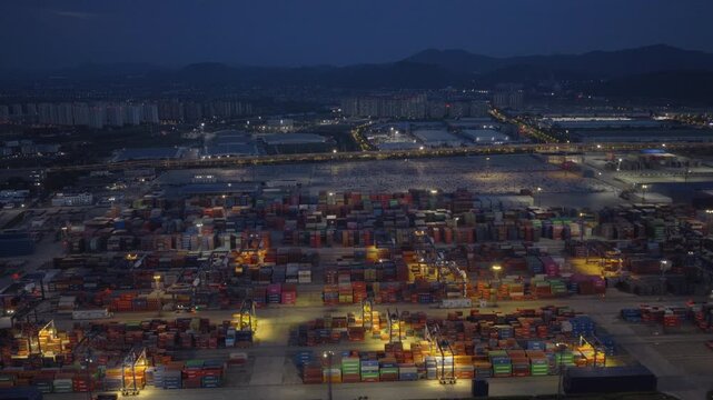 Dusk aerial view of illuminated port logistics area and vehicle export yard