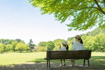 Fototapeta premium 木陰のベンチで休む二人の暑さ対策