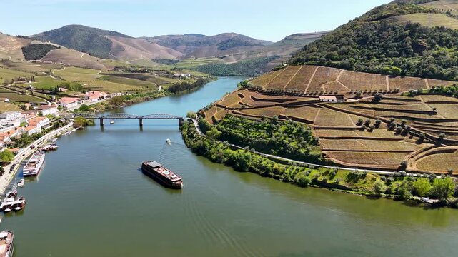 Aerial view of the Douro River flowing through terraced vineyards and the town of Pinhao, Vila Real, Portugal.