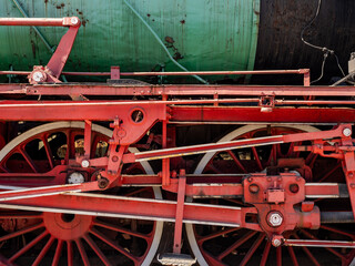 Close-Up Of Red Steam Locomotive Wheels And Mechanism On Vintage Green Boiler © Michał Kiełbicki