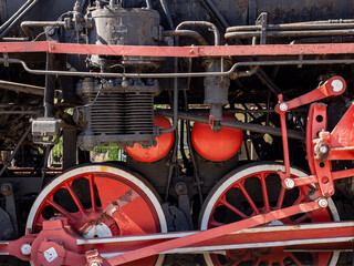 Close-Up Of Vintage Steam Locomotive Wheels And Red Mechanical Pistons On Rusted Engine © Michał Kiełbicki