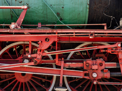 Close-Up Of Red Steam Locomotive Wheels And Mechanism On Vintage Green Boiler