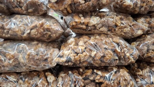 Shelled walnuts packed in transparent plastic bags close up. Stack of organic nut kernels in cellophane packaging on a supermarket shelf, healthy snack retailing and bulk grocery supply concept