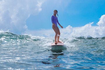 Fototapeta premium Young Woman Gliding On Gentle Swell, Contemplative Posture And Calm Ocean Mood With Clear Sky And Reflective