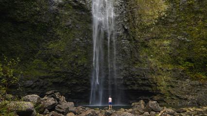 A person standing in front of a huge waterfall in Hawaii © A Beautiful World