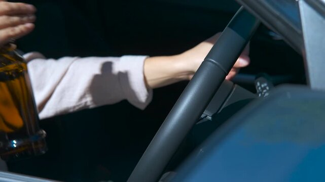 Woman drinking beer while driving a car. Intoxicated female driver holding beer bottle while operating vehicle, demonstrating dangerous and illegal behavior threatening road safety