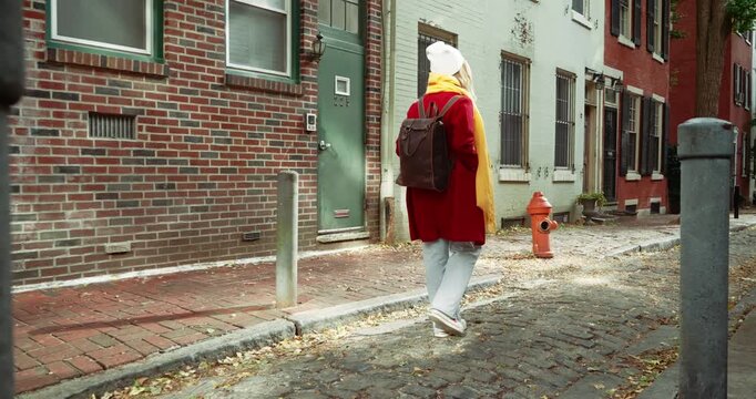 Woman Walking Down Cobblestone Street in Urban Setting