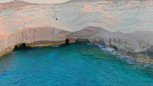 Aerial view of the unique white volcanic rock formations and turquoise Aegean Sea at Sarakiniko Beach in Milos, Greece.