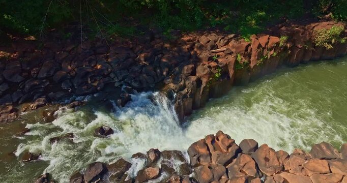 Aerial view of Tad Pha Suam Waterfall near Pakse in Champasak Southern Laos. Water flows over unique column like rock formations surrounded by lush tropical forest, creating a scenic natural