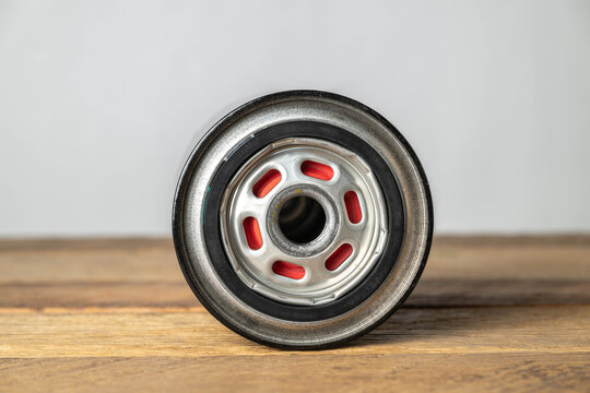 New, replacement oil filter for an automobile on wooden work bench in a garage, bottom view.
