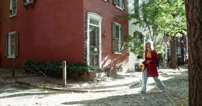 Woman Walking Down Cobblestone Street in Historic Neighborhood