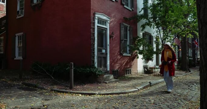 Woman Walking on Cobblestone Street in Quaint Neighborhood