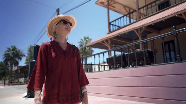 Mature woman walks by a the Francis hotel and enjoys various sights in Santa Rosalia, Baja California Sur Mexico while interacting with the local environment.