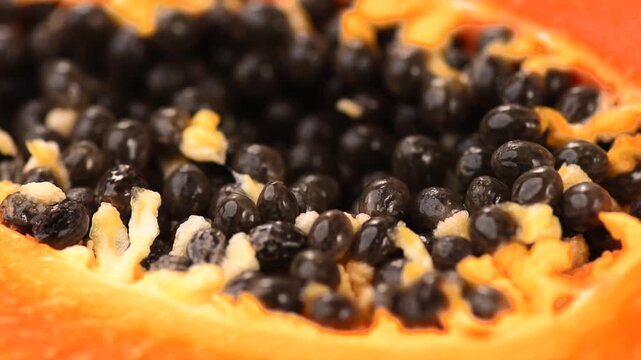 Papaya fruit pulp with seeds, macro background. Halved fresh organic Papaya exotic fruit design, close up, macro shot, rotating. 