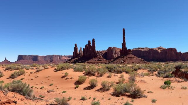 Iconic totem pole butte and yei bi chei spires standing in the vast desert landscape of monument valley navajo tribal park, a famous destination on the utah and arizona border