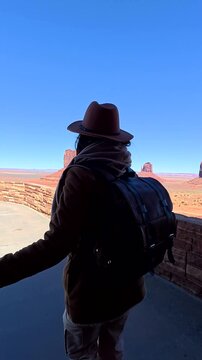 Female explorer opening a door and walking onto a scenic overlook, revealing the stunning panoramic landscape of monument valley, an iconic american southwest desert landmark under a clear blue sky