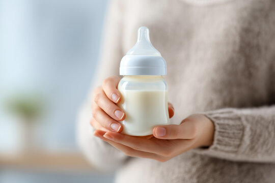 Woman hand holding a baby bottle of milk