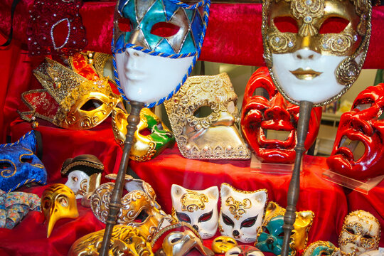 Traditional Ornate Carnival Masks arranged on a red fabric Displayed in Venice Italy