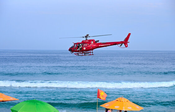Rescue helicopter of the Rio de Janeiro Fire Department (CBMERJ) carrying out an operation on the beach. Concept of search and rescue, first aid in maritime areas, helicopter evacuation and emergencie