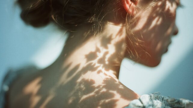 女性の首筋に植物の影が映っている写真。自然光を活かしたナチュラルで繊細な表現に適したイメージ素材