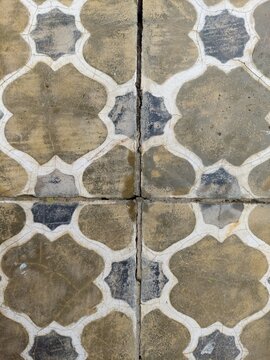 Close-up of old vintage hydraulic floor tiles with geometric floral patterns and natural cracks