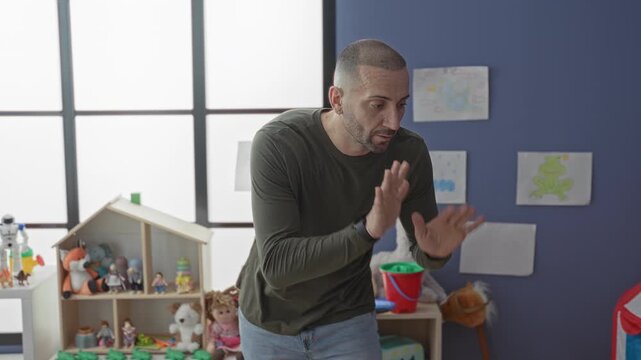 Man with hands gesturing and finger to lips for silence in a kindergarten playroom in a school building; patience classroom guidance.