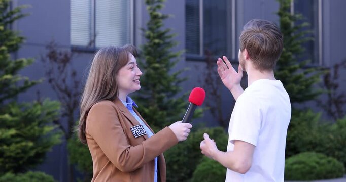 Professional journalist with microphone interviewing man outdoors