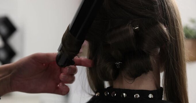 Hairdresser styling woman's hair in beauty salon, closeup