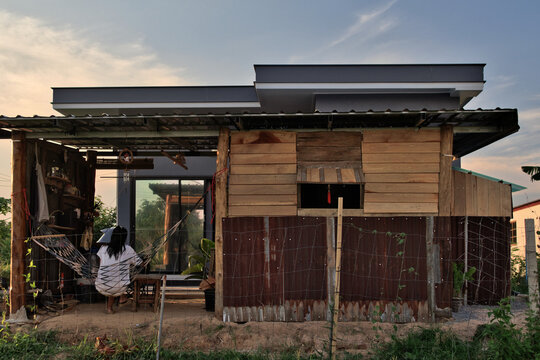 Modern DIY wooden cabin extension with rustic zinc wall and metal sheet roof.
