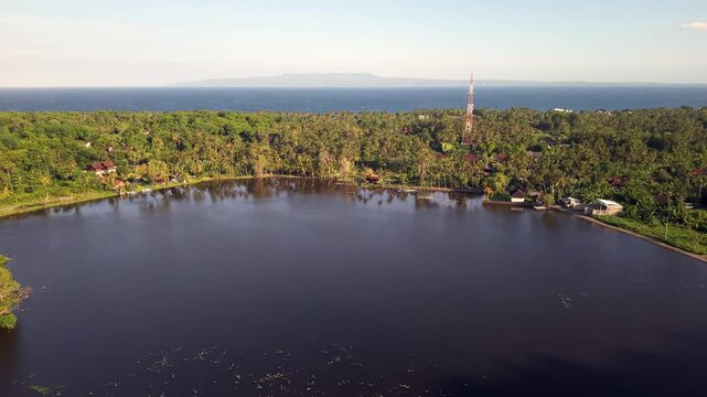 Aerial View of Danau Yeh Malet Lake with Tropical Palm Forest and Ocean Horizon