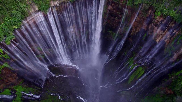 Spectacular aerial view of Tumpak Sewu Waterfall cascading down lush green cliffs in Lumajang