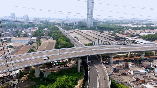 Vibrant aerial view of an elevated highway overpass with power lines and urban industrial landscape during a descending shot
