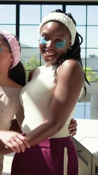 Vertical video: Smiling woman posing with gel patches and headbands, friend entering left by window