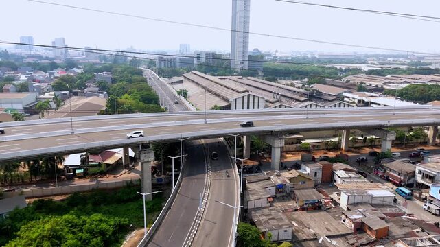 Vibrant aerial view of an elevated highway overpass with city skyline and power lines in a busy industrial district.