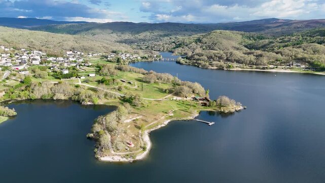 Aerial view of Encoro de Prada reservoir surrounded by green hills and houses in A Veiga, Ourense, Spain.