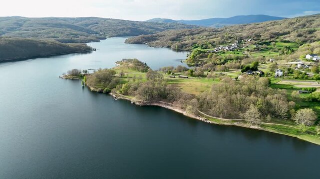 Aerial view of Encoro de Prada reservoir surrounded by lush green forests and rolling hills in A Veiga, Ourense, Spain.