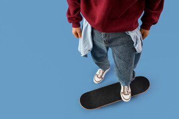 Young man with skateboard on blue background, closeup © Pixel-Shot