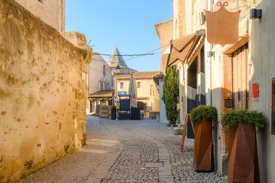 A narrow cobblestone street of shops and cafes in La Cite' within the fortified walls of the historic castle of Carcassonne in France.