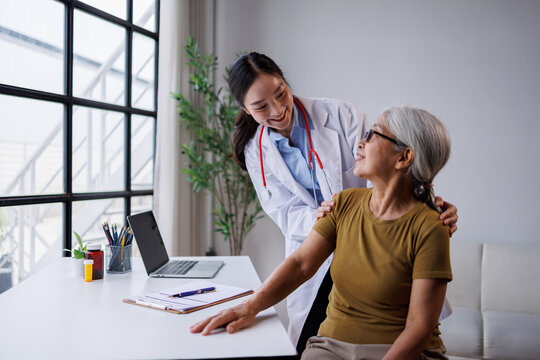 Young asian woman doctor providing compassionate care and support to an elderly female patient during a routine medical checkup in a modern clinic setting