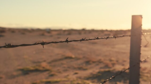 Barbed wire fence at sunset in a desert landscape