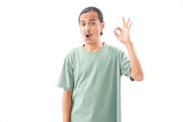 young handsome Indonesian, Asian man in green shirt OK or approved sign with fingers and gesture...