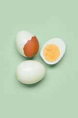 Tasty boiled eggs with half on green background