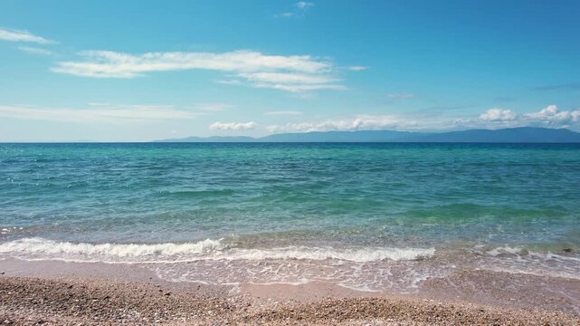 Aerial view of the turquoise sea and sandy beach under a clear blue sky in Paralia Ofriniou, Greece.