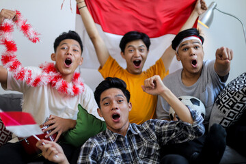 Obraz premium Group of passionate Indonesian Football Fans Shouting and Cheering with National Flag and Ball