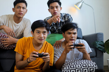 Obraz premium Group of Focused Young Men Playing Video Games Together at Home